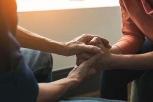 people clasp hands in addiction treatment programs