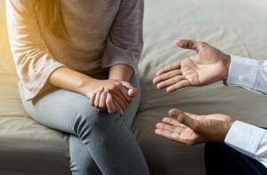 Woman sitting on couch in therapeutic setting learning about medication-assisted treatment