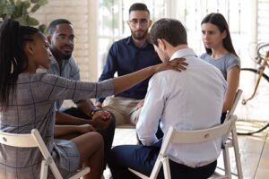 woman puts hand on shoulder of man in addiction treatment therapies